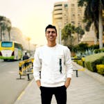 Smiling young man posing confidently on a city street during the day.